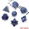 A set of seven blue sodalite crystals, including geometric shapes and a sphere, displayed on a white background.