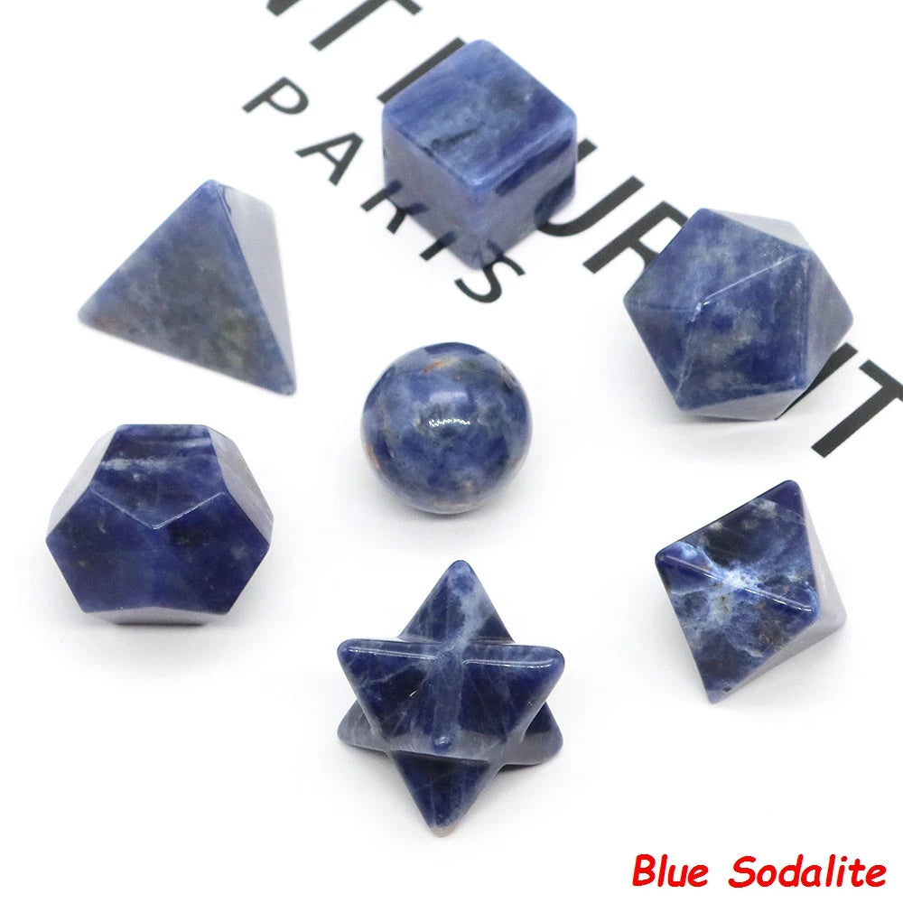 A set of seven blue sodalite crystals, including geometric shapes and a sphere, displayed on a white background.