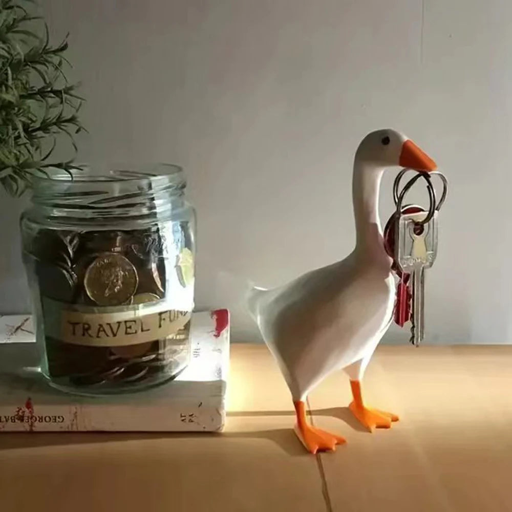 A white goose figurine with orange legs and a magnetic key holder attached to its neck.