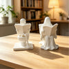 White ceramic statue depicting a skeleton ghost reading a book on a toilet bowl