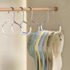 A wooden hanger bar holds several round metal hooks displaying various colored hats, ties, and scarves.