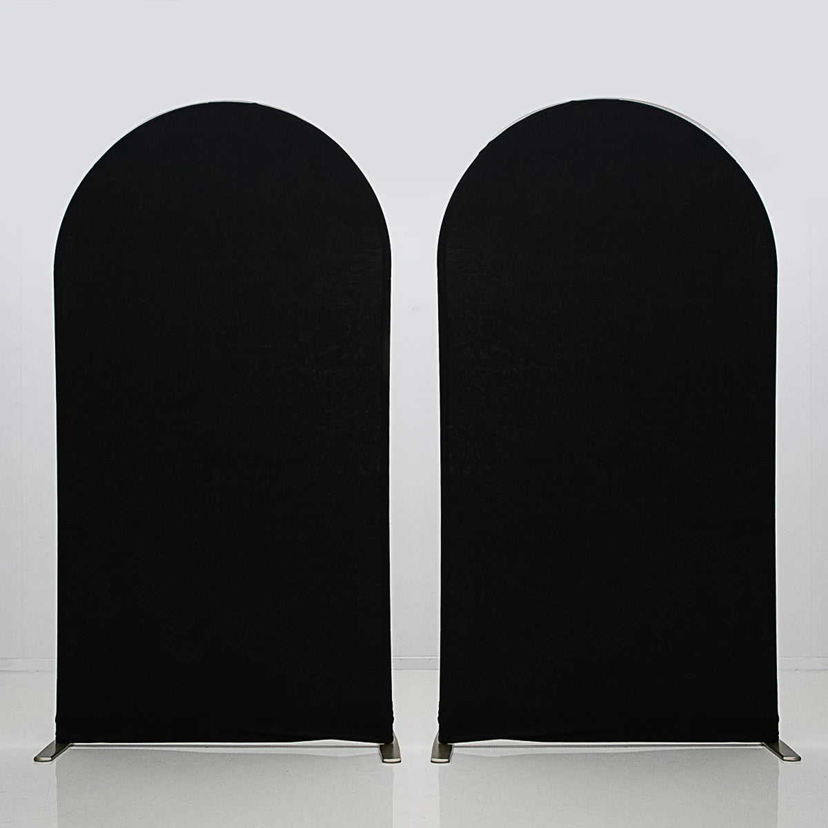 Two black stretchable arch backdrop covers standing upright against a white background.