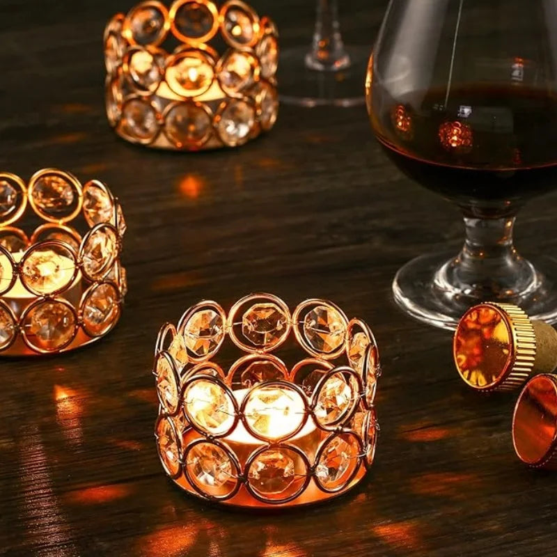 A close-up of a crystal tealight candle holder with a metal base resting on a dark wooden surface.
