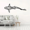 Black metal line sculpture of a shark swimming, mounted on a white wall above a light gray sofa.