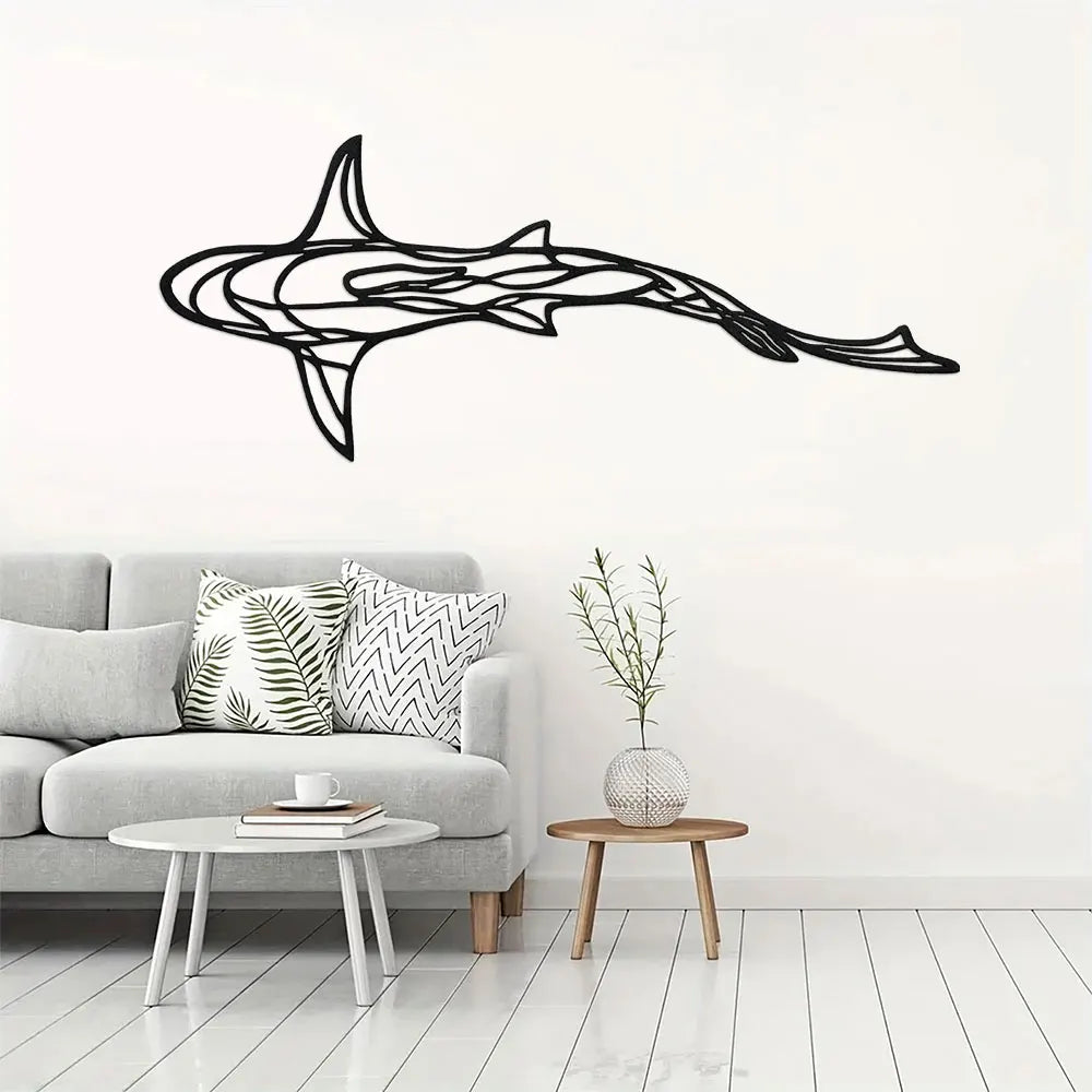 Black metal line sculpture of a shark swimming, mounted on a white wall above a light gray sofa.
