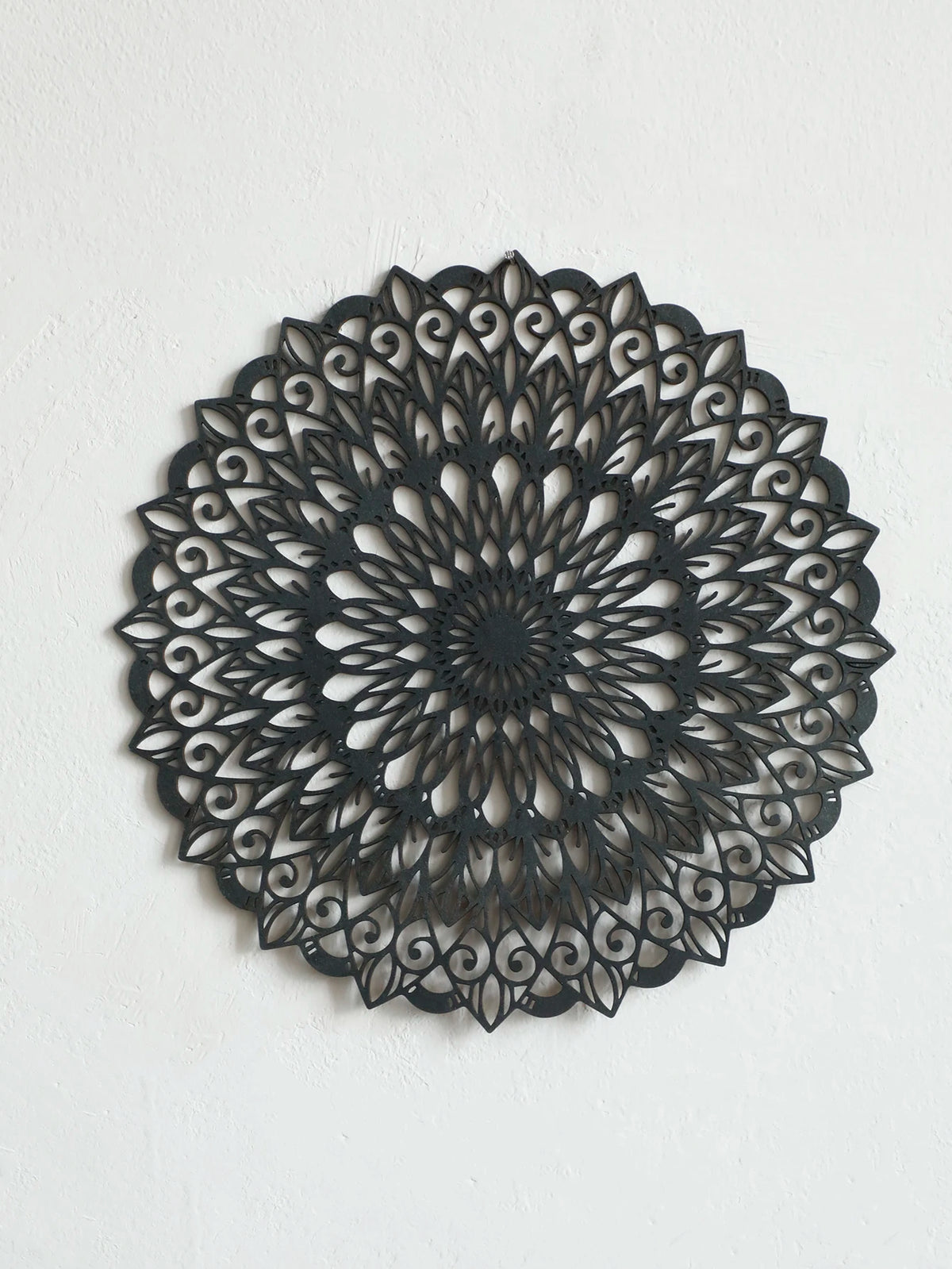 Decoración de pared colgante de madera negra con intrincados patrones de pergamino repetitivos.