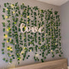 Artificial leaf string lights creating a green vine backdrop with the word love