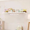 A set of wavy wooden floating shelves displaying children's books and a wooden figurine on a white wall.