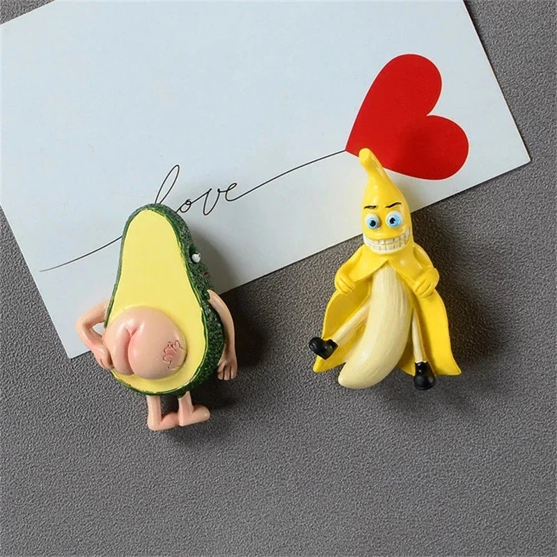 A set of cute 3D fruit fridge magnets featuring a banana and an avocado, with a red heart in the background.