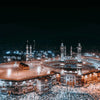 A panoramic night view of the Masjid an Nabawi in Mecca, showing architecture and crowds.
