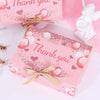Pink gift box with glitter and heart accents tied with a gold ribbon.