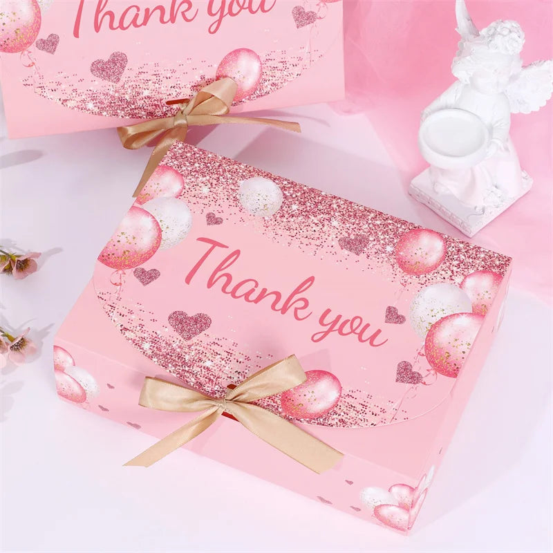 Pink gift box with glitter and heart accents tied with a gold ribbon.