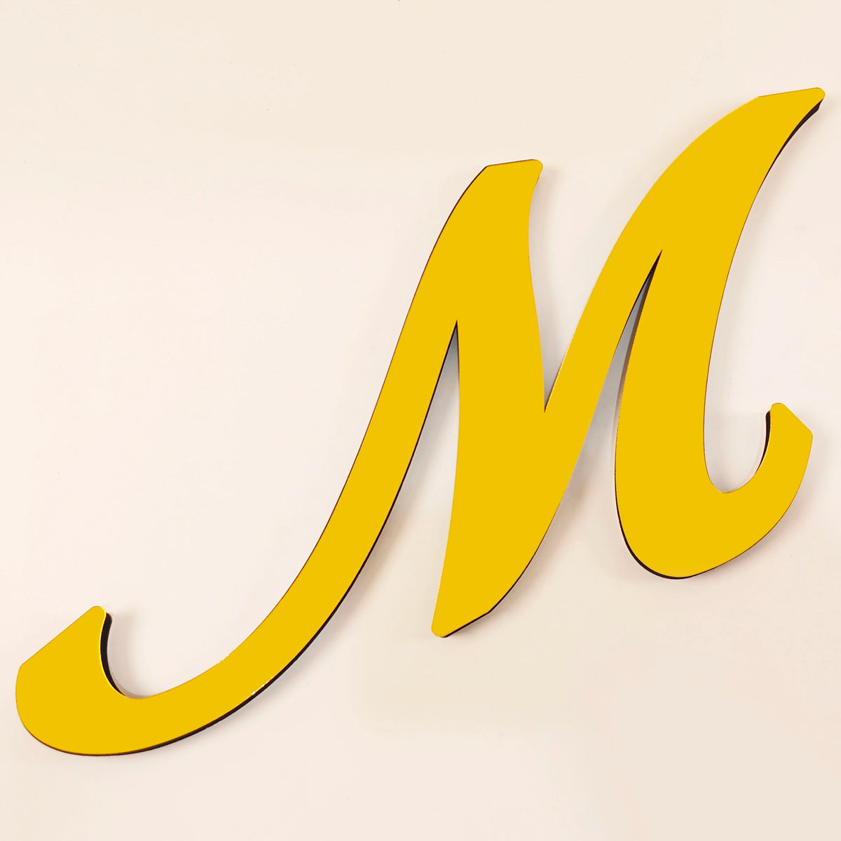 A large, yellow 3D acrylic letter M wall sticker against a light background.
