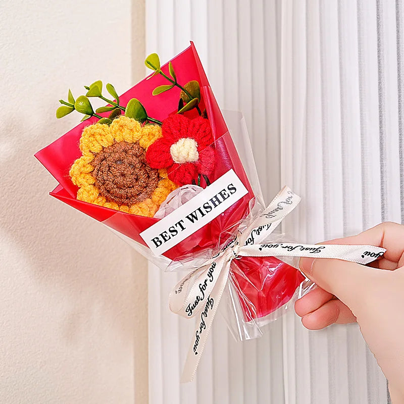 A bouquet of handmade crochet flowers in red and yellow velvet blooms wrapped in clear cellophane with a best wishes tag.