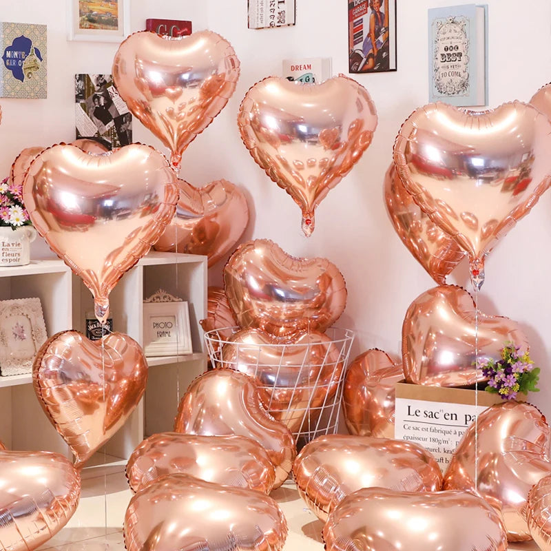 A collection of rose gold heart foil balloons displayed against a white wall.