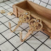 A pair of vintage gold-toned crown curtain hooks with small clear stones resting on a wooden tray.