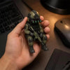 A hand holds a detailed resin collectible statue of a tactical sniper soldier figurine.