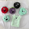 A collection of fuzzy plush keychains in various colors including red purple green and black on white paper