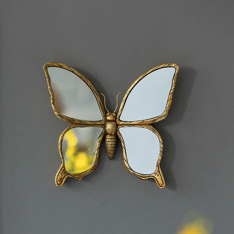 An artisan butterfly wall mirror featuring a white butterfly design with an antique gold frame.
