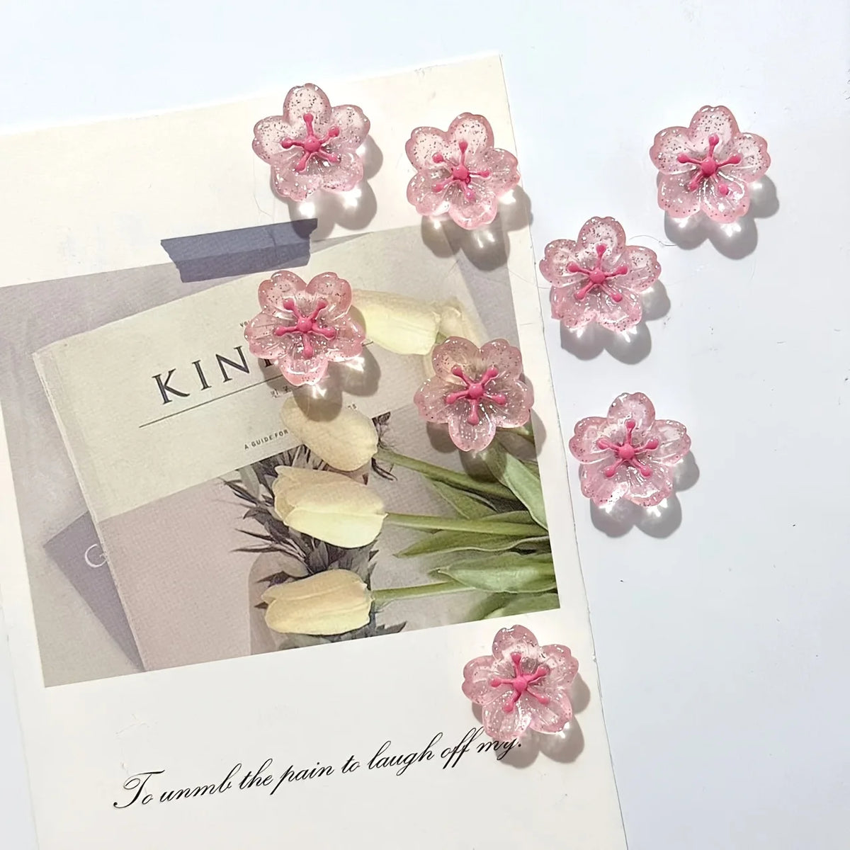 Pink cherry blossom fridge magnets with soft shadows on a light background.