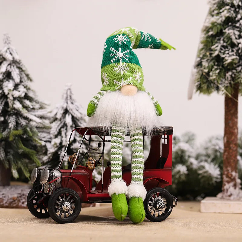 A festive green and white gnome decoration stands next to a vintage red wagon in a snowy outdoor setting.