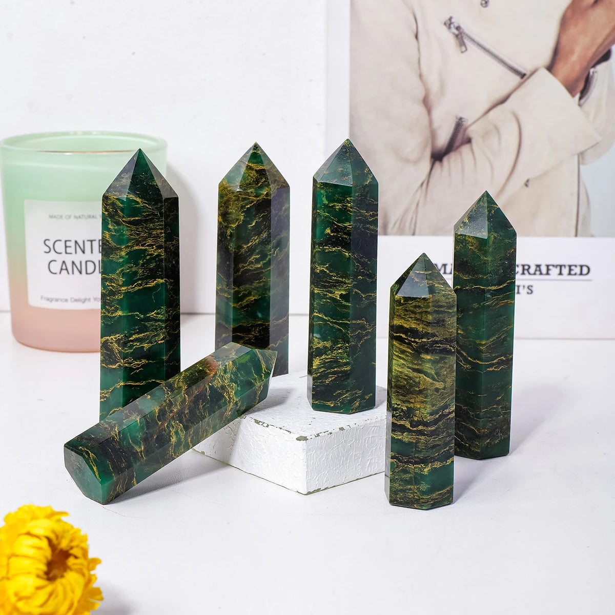 A collection of dark green emerald crystal point healing wands displayed on a white surface.