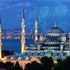 A nighttime view of a mosque with minarets and a large dome silhouetted against a twilight sky.