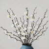 Ramitas de flor de ciruela blanca artificial en un jarrón de cerámica azul para decoración del hogar