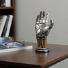 A metallic hand-shaped storage organizer for a 3D gamepad or controller, resting on a wooden surface.