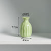 A light green ceramic mini vase with a narrow neck and rounded body, shown against a white background.