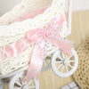 A white faux rattan woven storage basket with a pink satin ribbon is shown from the side.