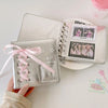 A silver leather photo album with a pink ribbon is shown next to a clear plastic photo insert.