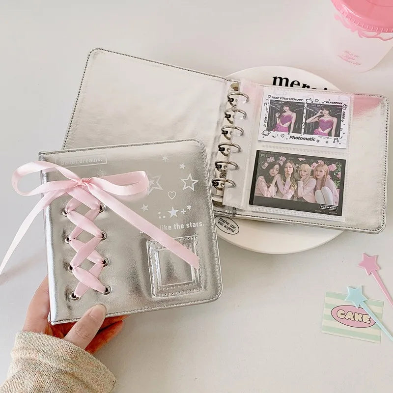 A silver leather photo album with a pink ribbon is shown next to a clear plastic photo insert.