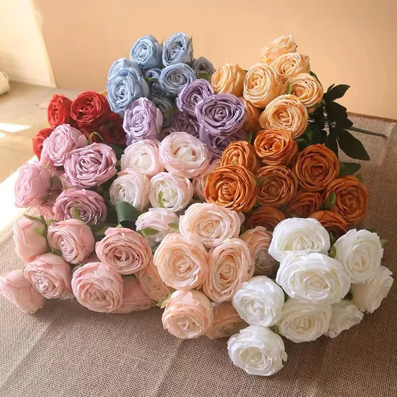 A vibrant bouquet of silk roses in shades of blue, purple, pink, and orange arranged for weddings or home decor.