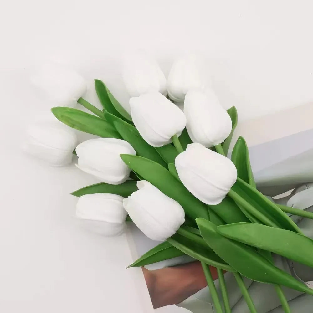 A bouquet of white artificial tulips with green stems and leaves
