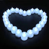 A heart shape formed by a ring of white LED tea light candles