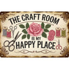 A vintage metal sign with the text The Craft Room is my happy place surrounded by roses and gardening tools.