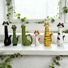 A collection of cat-shaped resin figurines in various colors and styles displayed on a white windowsill.