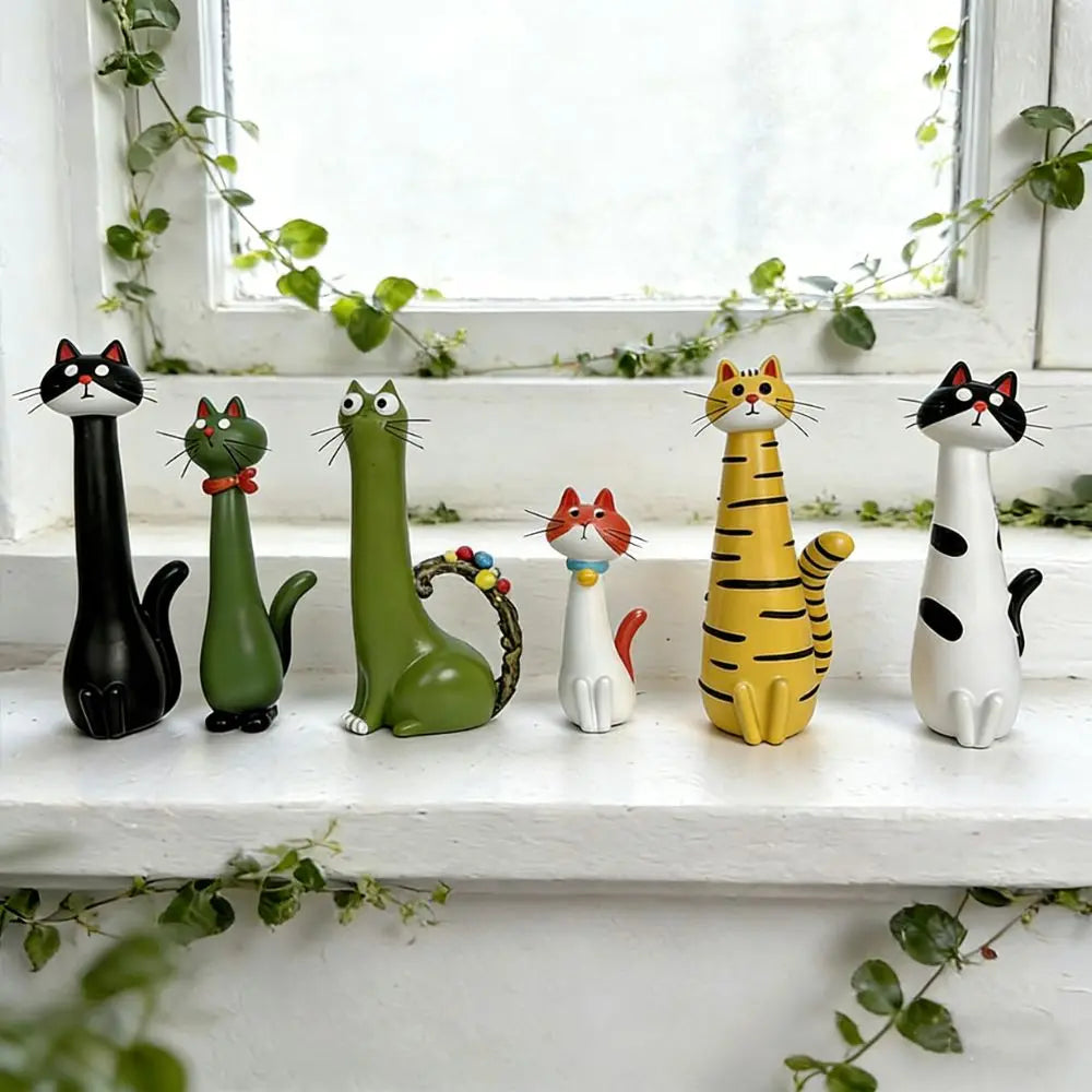 A collection of cat-shaped resin figurines in various colors and styles displayed on a white windowsill.
