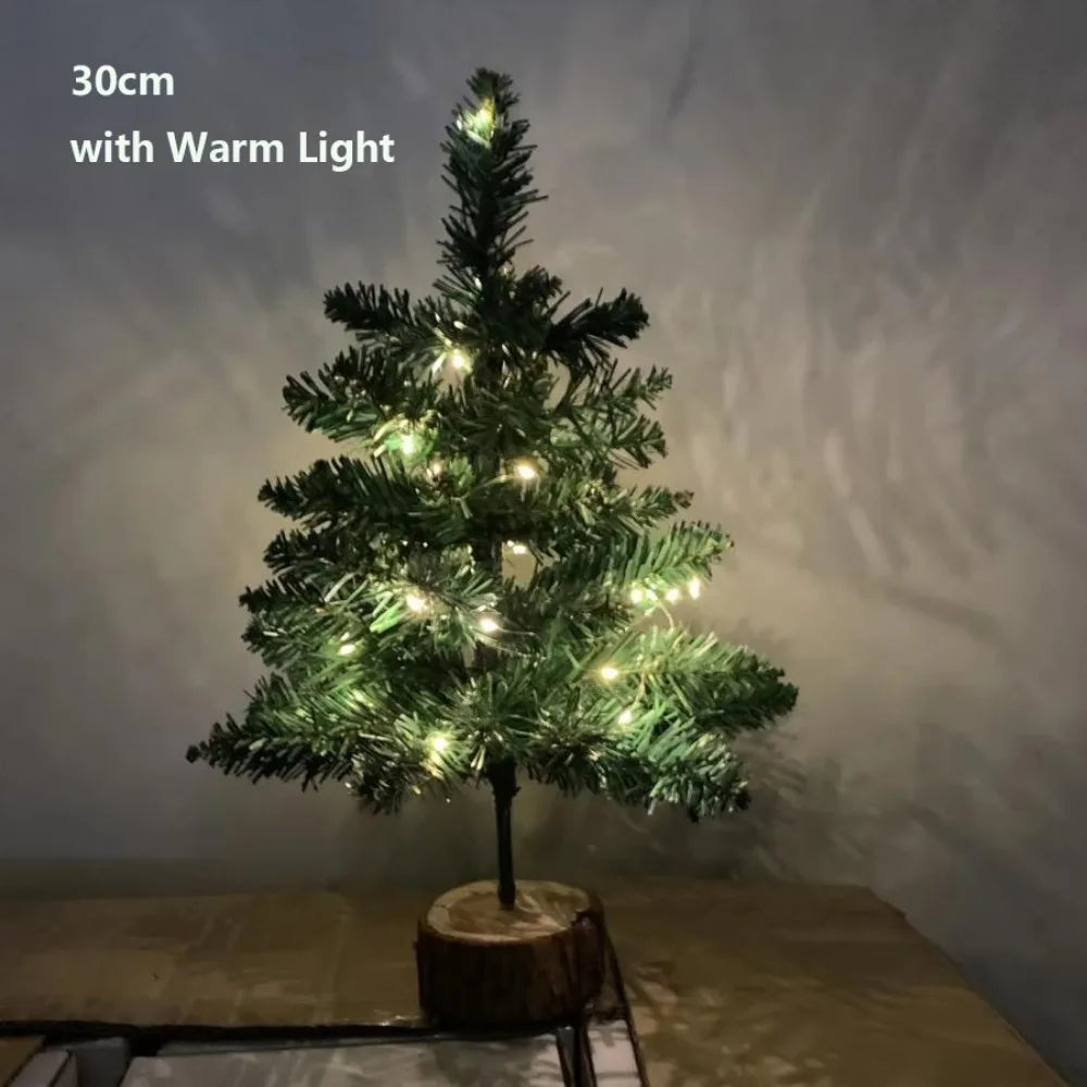 A small, decorated Christmas tree with warm lights standing on a wooden base.