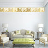 A living room features a light gray sofa, a lime green ottoman, and a gold decorative mirror trim on the white wall.