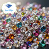 A close-up of a scatter of colorful acrylic diamond gemstones in various shades of pink, purple, green, and clear white.