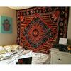 A large bohemian mandala tapestry wall hanging featuring intricate geometric patterns in black, orange, and gold on a dark ba