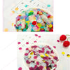 A bowl filled with multicolor paper confetti scattered on a white surface with a die showing the word FAITH.