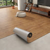 Roll of 3D textured wood grain self-adhesive flooring film laid on a light gray floor.