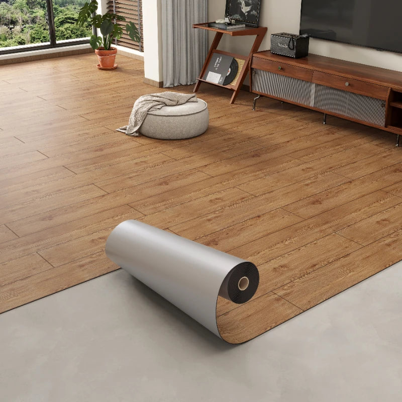 Roll of 3D textured wood grain self-adhesive flooring film laid on a light gray floor.