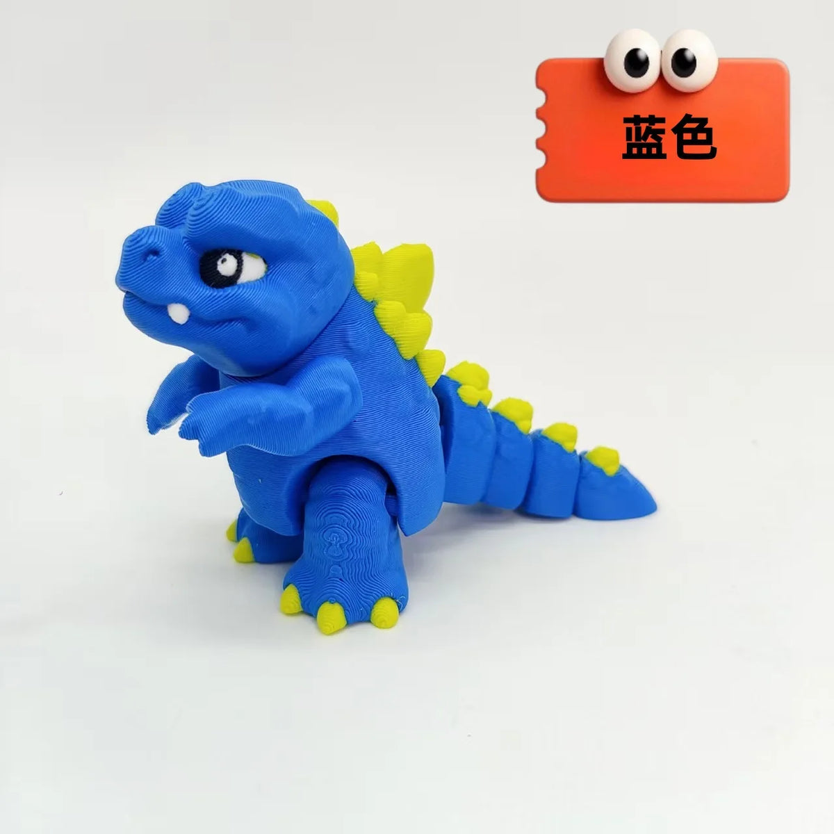 A blue 3D printed Godzilla sitting figure next to an orange color swatch card.