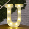 A glowing warm white LED alphabet letter light shaped like the letter U, illuminating the surface below.