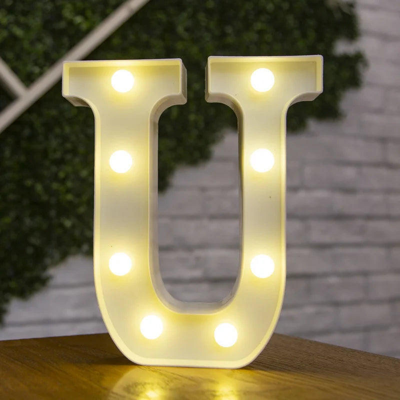 A glowing warm white LED alphabet letter light shaped like the letter U, illuminating the surface below.