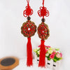 Red and gold mystic knot wall decor featuring tassels and circular designs